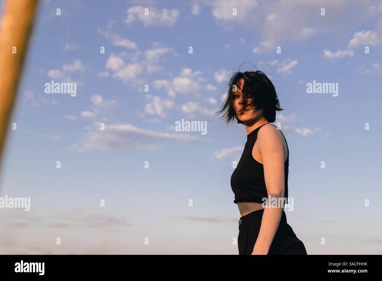 Bold Woman in Black Ensemble Against a Dreamy Sky Stock Photo