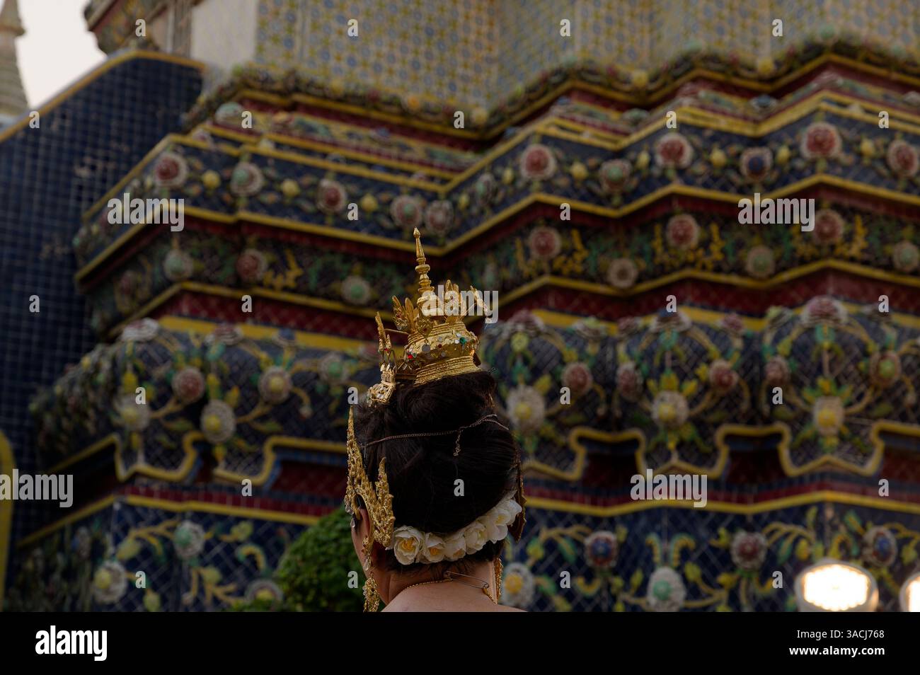 Traditional Thai headdress glimmers against the vibrant tiled stupas of Wat Pho Stock Photo