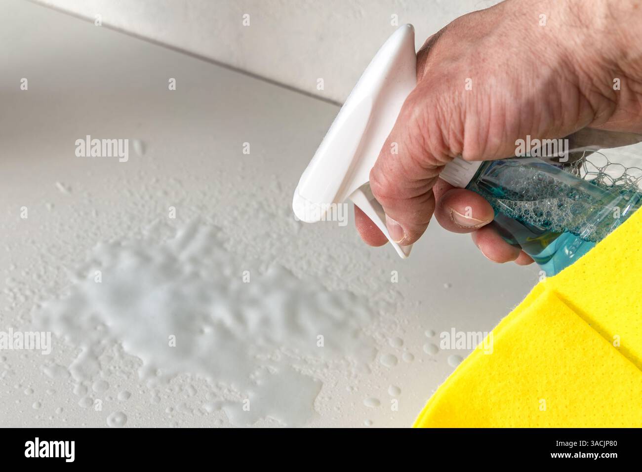 A container with a liquid for dusting furniture and a yellow microfiber cloth, tidying up the apartment before Easter Stock Photo