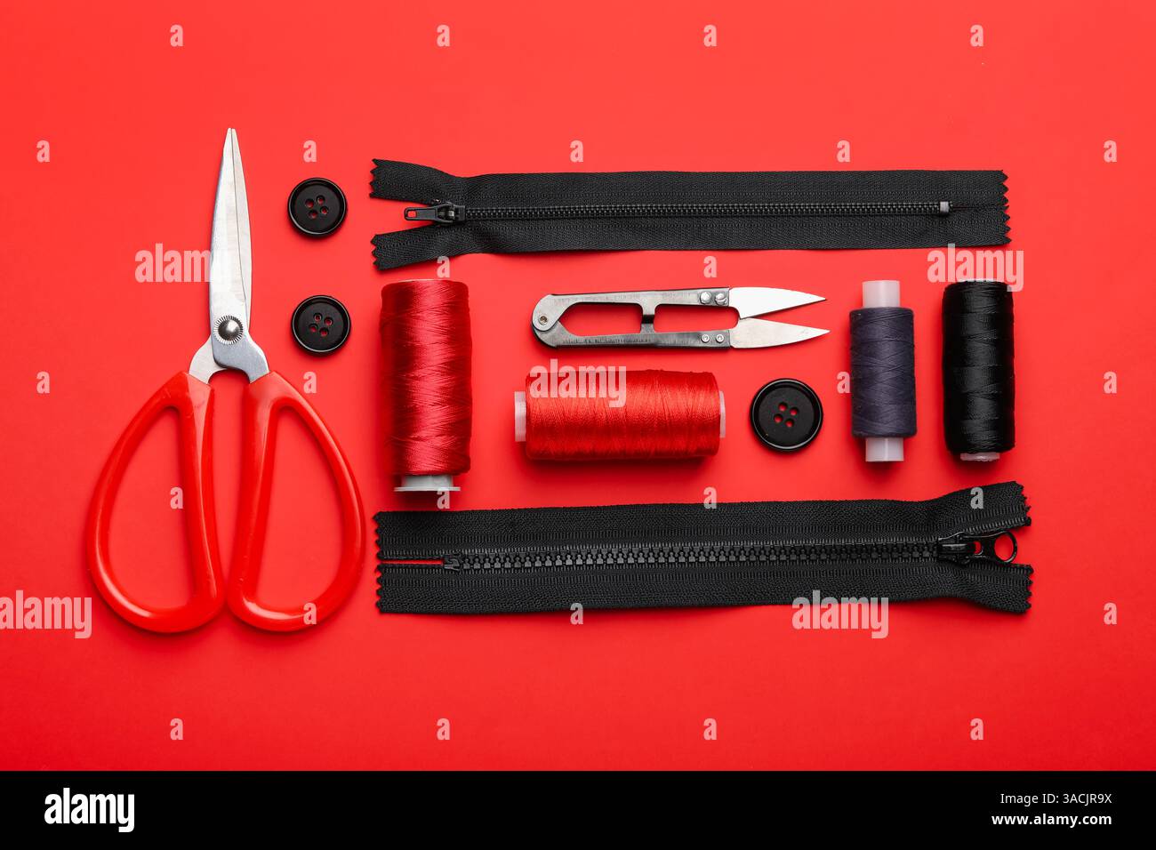 Different sewing supplies on red background, flat lay Stock Photo