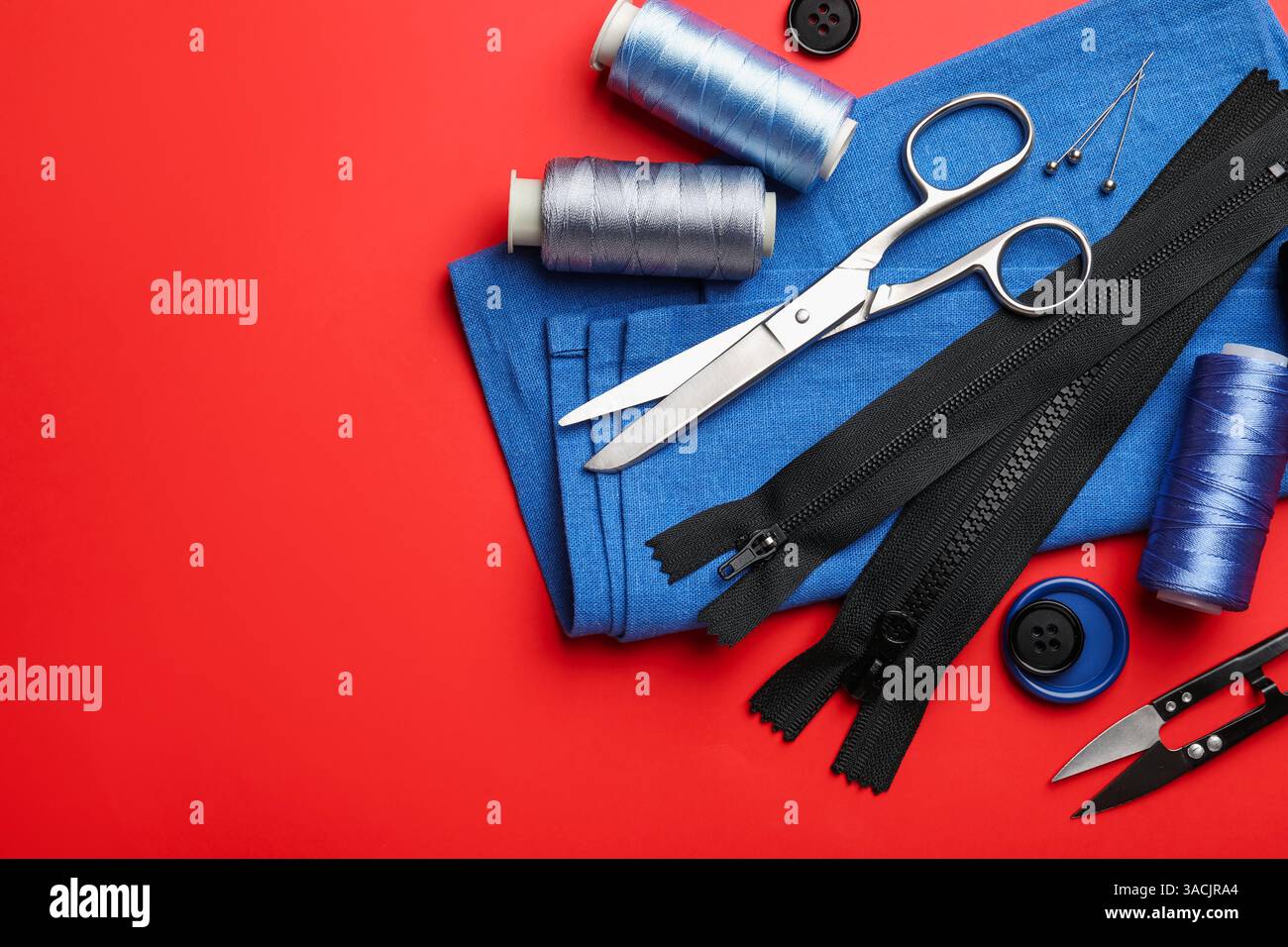 Different sewing supplies on red background, flat lay. Space for text Stock Photo
