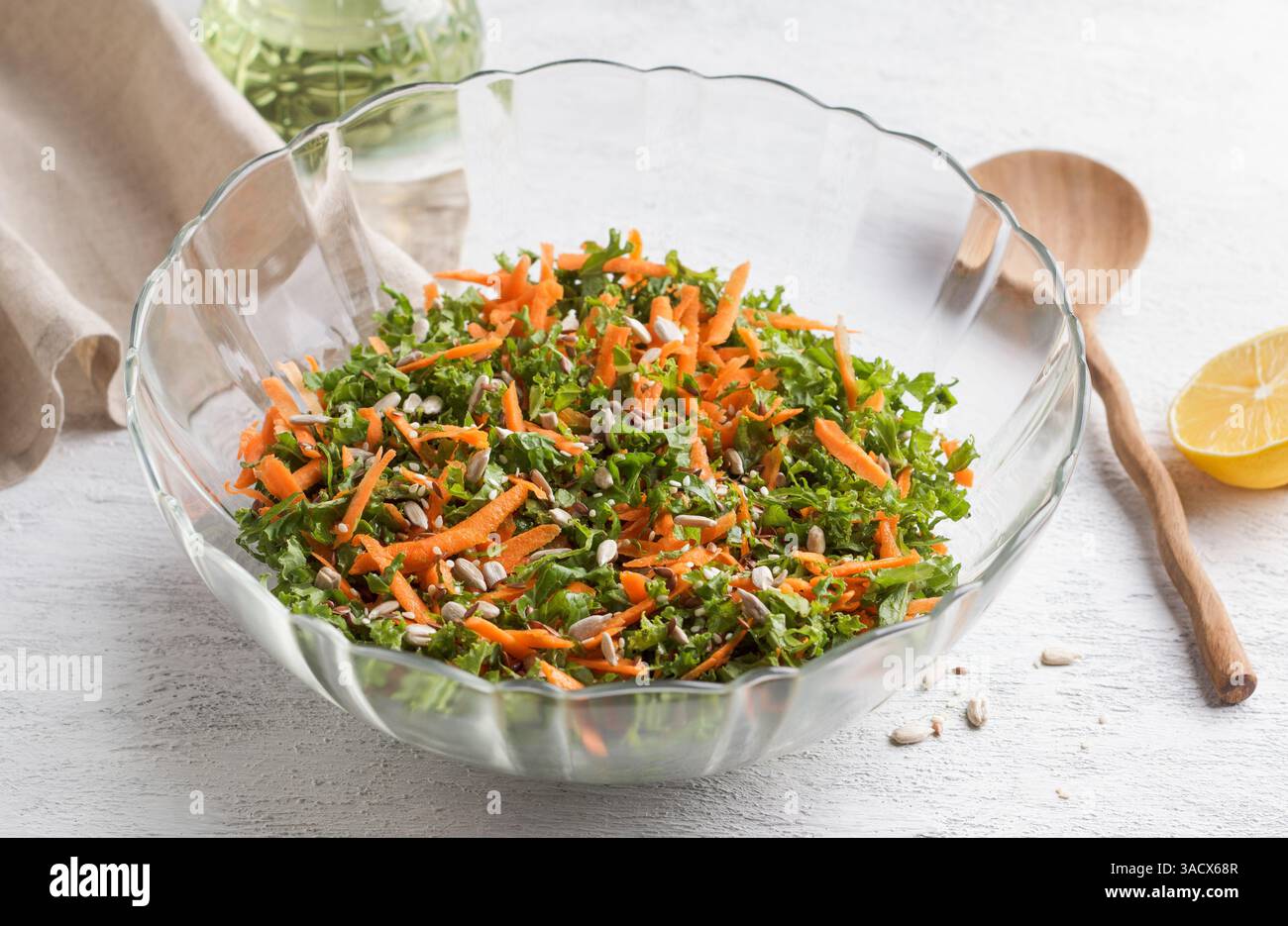 Chopped kale leaves with carrots in a transparent salad bowl on a light gray background Stock Photo