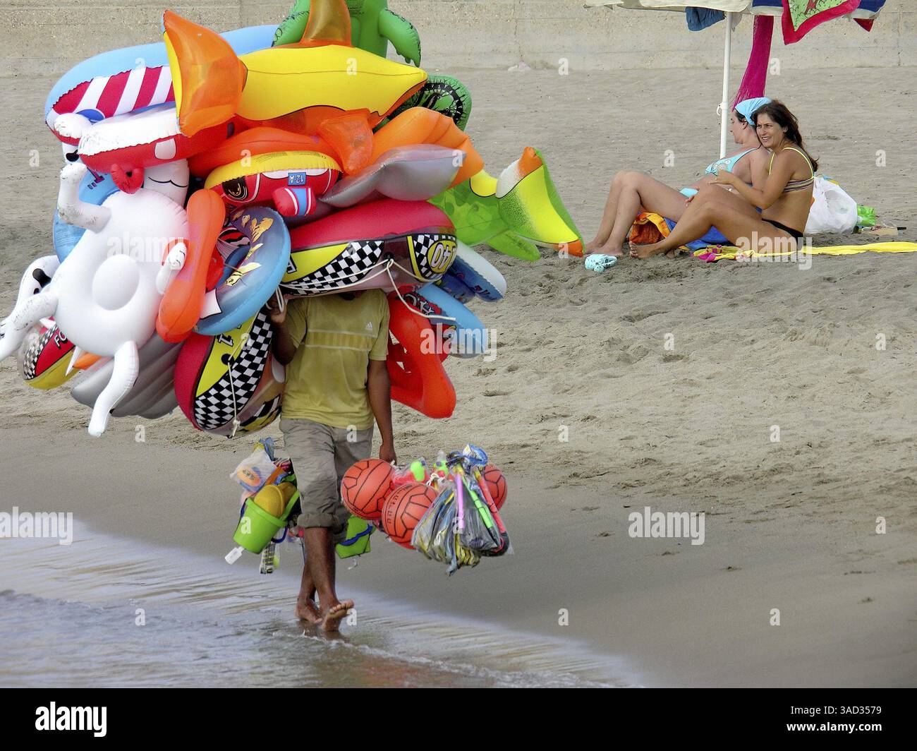 Flying merchant, seller overloaded with large quantities of beach toys ...