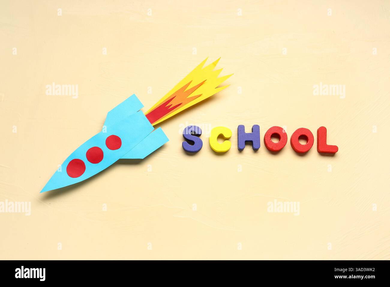 Paper rocket with word SCHOOL on beige background Stock Photo