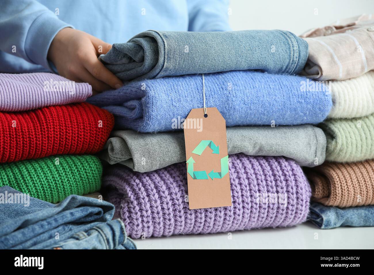 Woman stacking clothes with recycling logo on table, closeup Stock ...