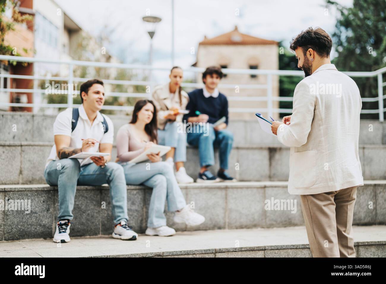 Students engaging in collaborative outdoor learning with helpful professor Stock Photo