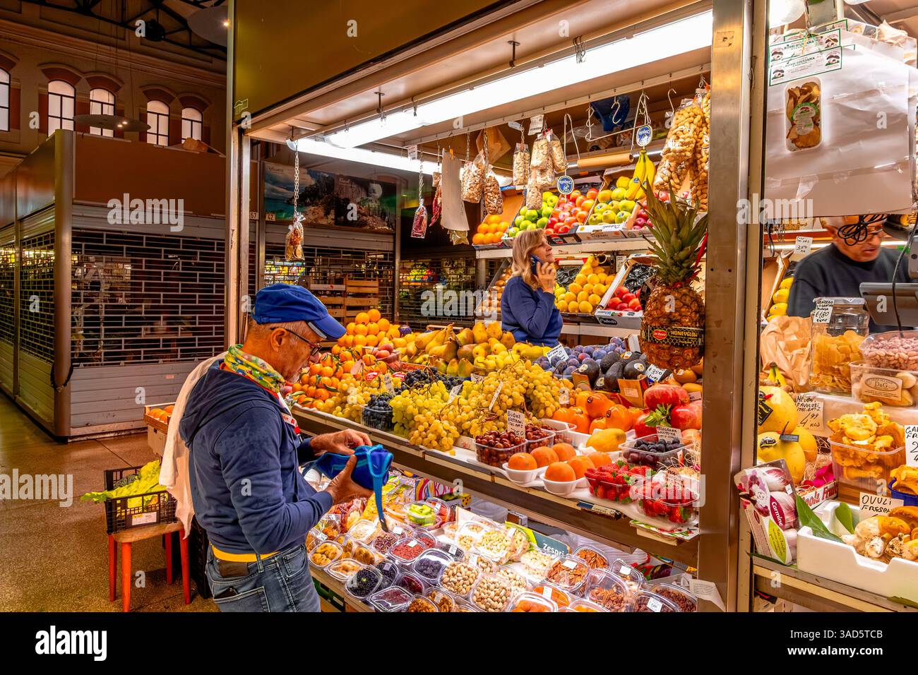 A man shopping for fruit and vegetables at a stall inside Mercato delle Erbe, a large indoor market in the historical city centre of Bologna,Italy Stock Photo