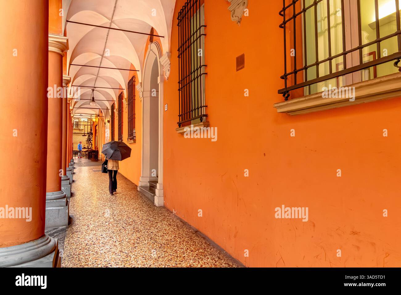A woman with an umbrella walking along  the elegant Portico on Via Nosedella in Bologna Italy Stock Photo