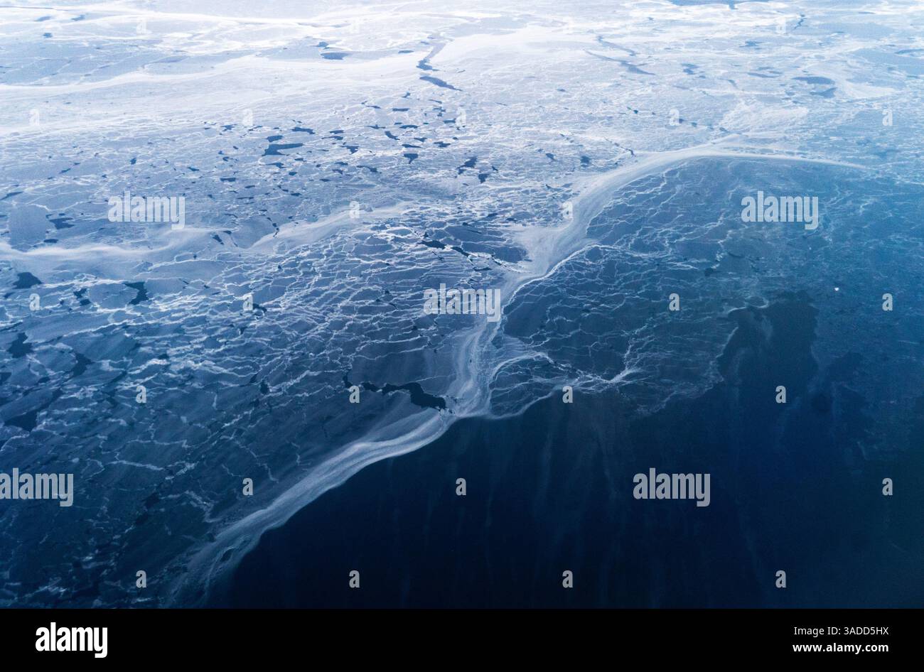 Aerial view of a frozen landscape with cracked ice patterns on a body ...