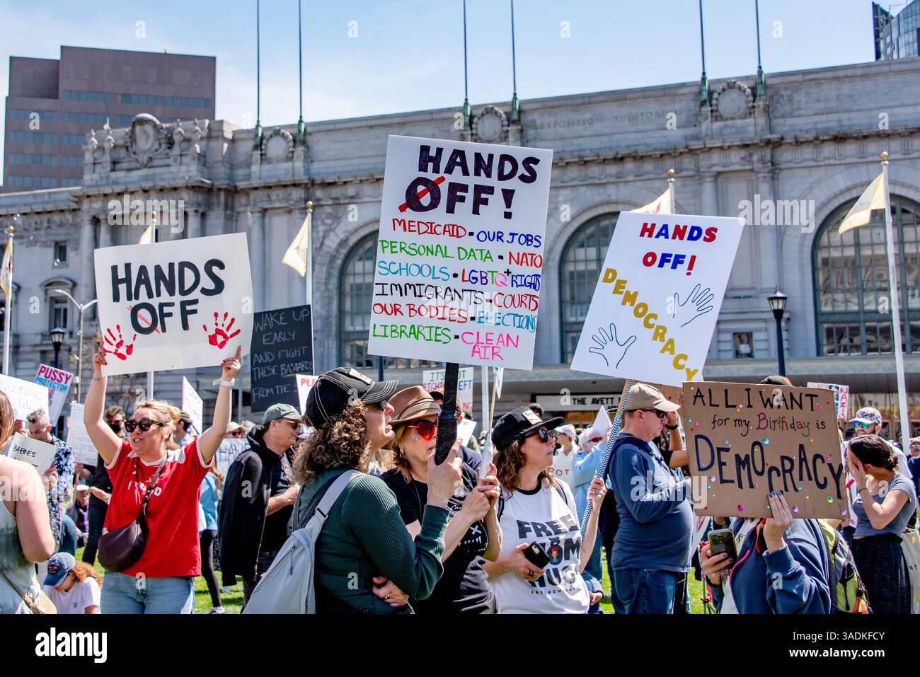 San Francisco, USA. 5th Apr 2025. Many protesters stand in San Francisco Civic Center Plaza during a Hands Off! protest against recent actions by Donald Trump and Elon Musk. Signs read, 'Hands Off,' 'Hands Off! Medicaid, Our Jobs, Personal Data, 'NATO, Schools, LGBTQ+ Rights, Immigrants, Courts, Our Bodies, Elections, Libraries, Clean Air,' and 'Hands Off! Democracy.' Credit: Shelly Rivoli/Alamy Live News - Stock Image