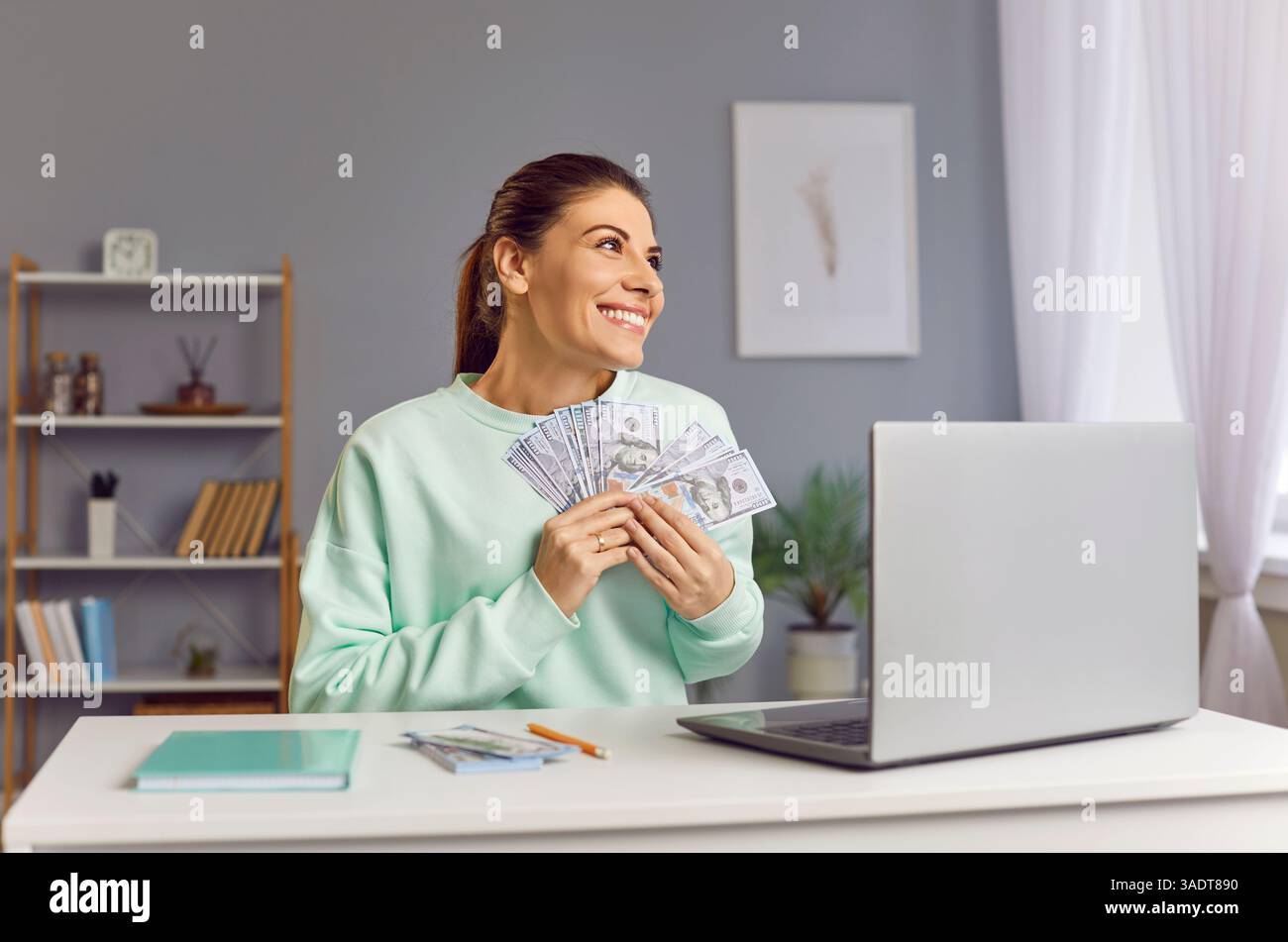 Happy smiling woman holding stack of cash money, celebrating winning lottery or business success. Stock Photo