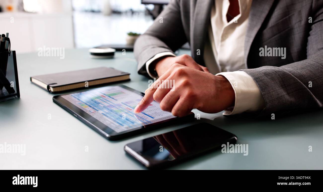 Young African American man analyzing data on computer spreadsheet software. Stock Photo