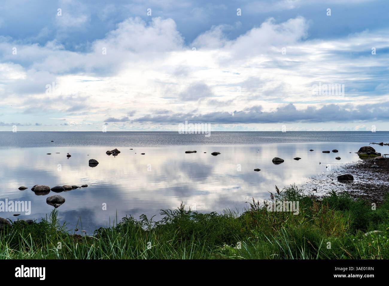 A serene landscape featuring a calm body of water reflecting the sky ...