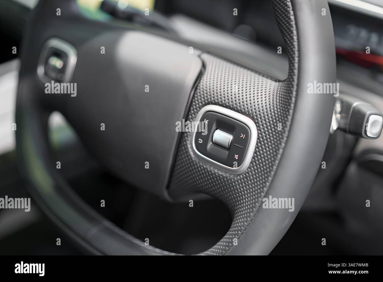 close-up of a modern steering wheel featuring a textured grip and built-in media controls, highlighting user-friendly automotive design and convenienc Stock Photo
