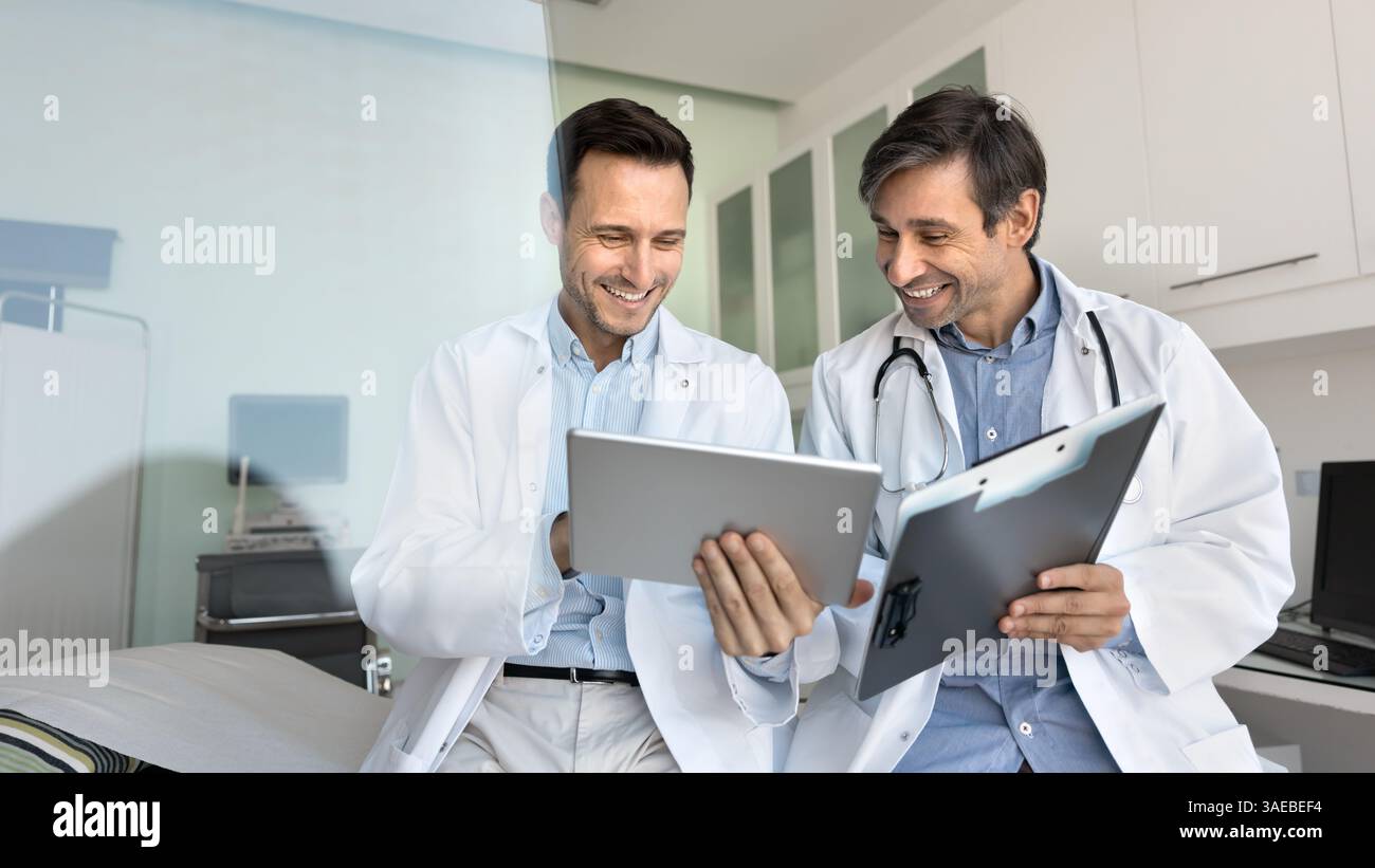 Two smiling male doctors in coats using digital tablet Stock Photo