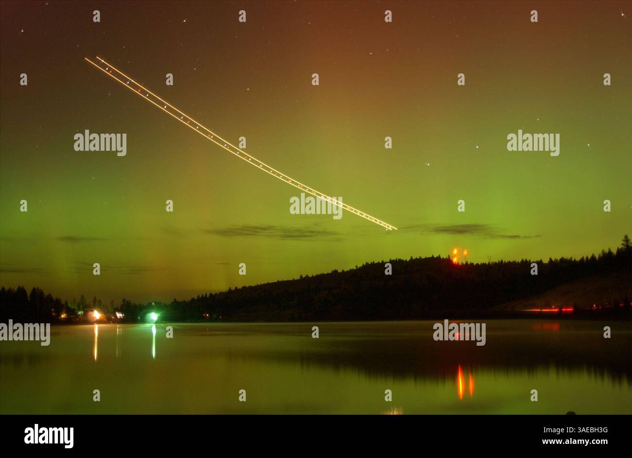 Oct 31, 2003; Kalispell, MT, USA; The northern lights dance green and red over Foys Lake near Kalispell, Montana. Aurora's are visible in areas across the world. The source of all this solar activity is giant sunspot 486. This week it unleashed two of the most powerful solar flares ever recorded and hurled massive coronal mass ejection's toward Earth. The streak of light in the sky is a jet coming in low for a landing at Glacier Park Internationl Airport..  (Credit Image: Robin Loznak/ZUMAPRESS.com) Stock Photo