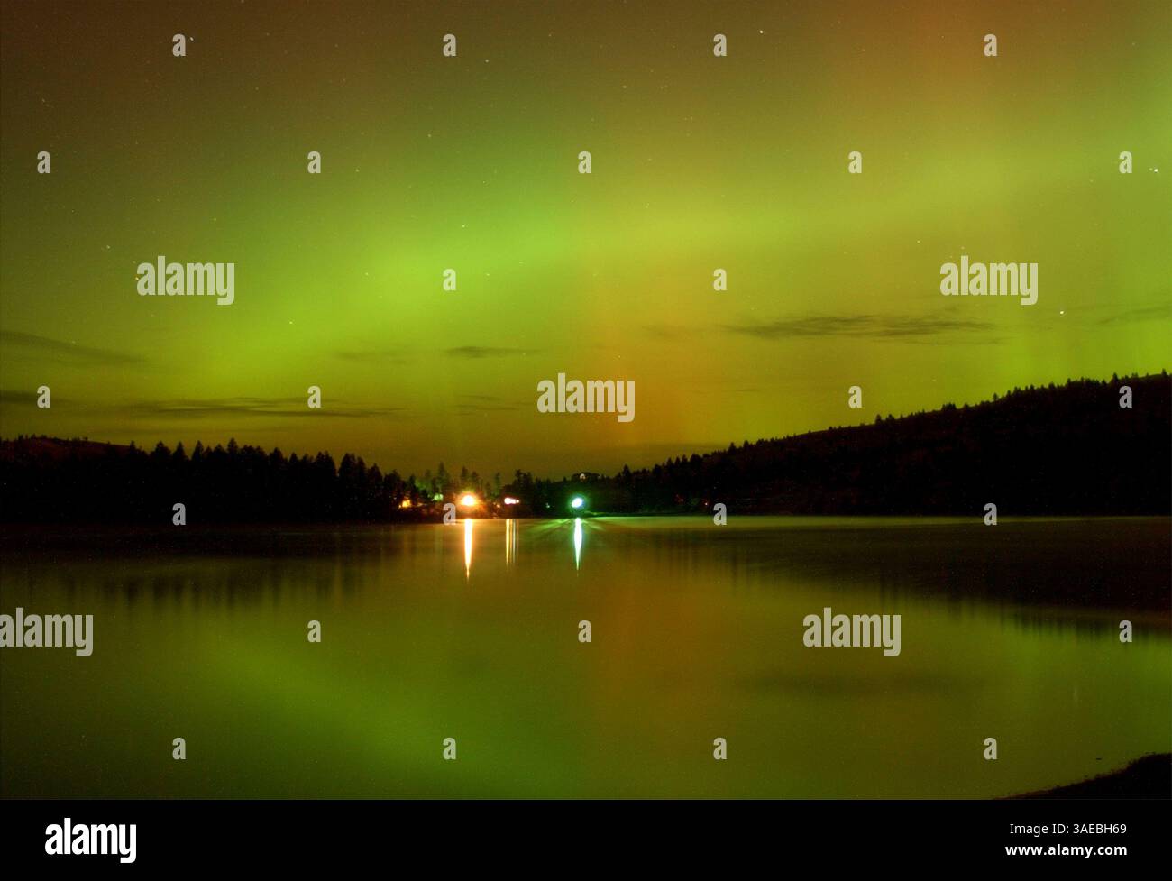 Oct 31, 2003; Kalispell, MT, USA; The northern lights dance green and red over Foys Lake near Kalispell, Montana. Aurora's are visible in areas across the world. The source of all this solar activity is giant sunspot 486. This week it unleashed two of the most powerful solar flares ever recorded and hurled massive coronal mass ejection's toward Earth. The streak of light in the sky is a jet coming in low for a landing at Glacier Park Internationl Airport..  (Credit Image: Robin Loznak/ZUMAPRESS.com) Stock Photo