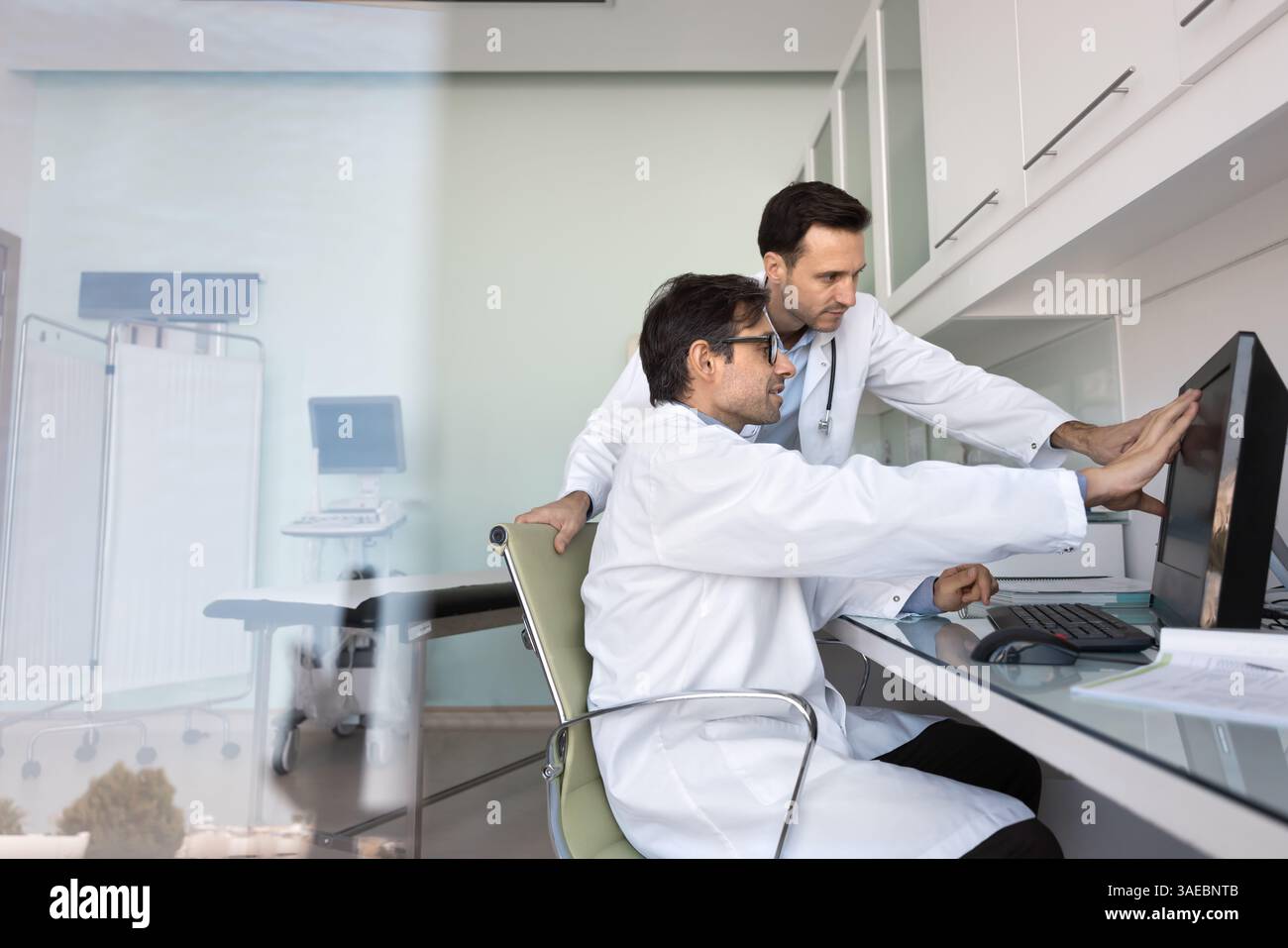 Computer Helping Doctors Two doctors discussing treatment options for patient using computer ...