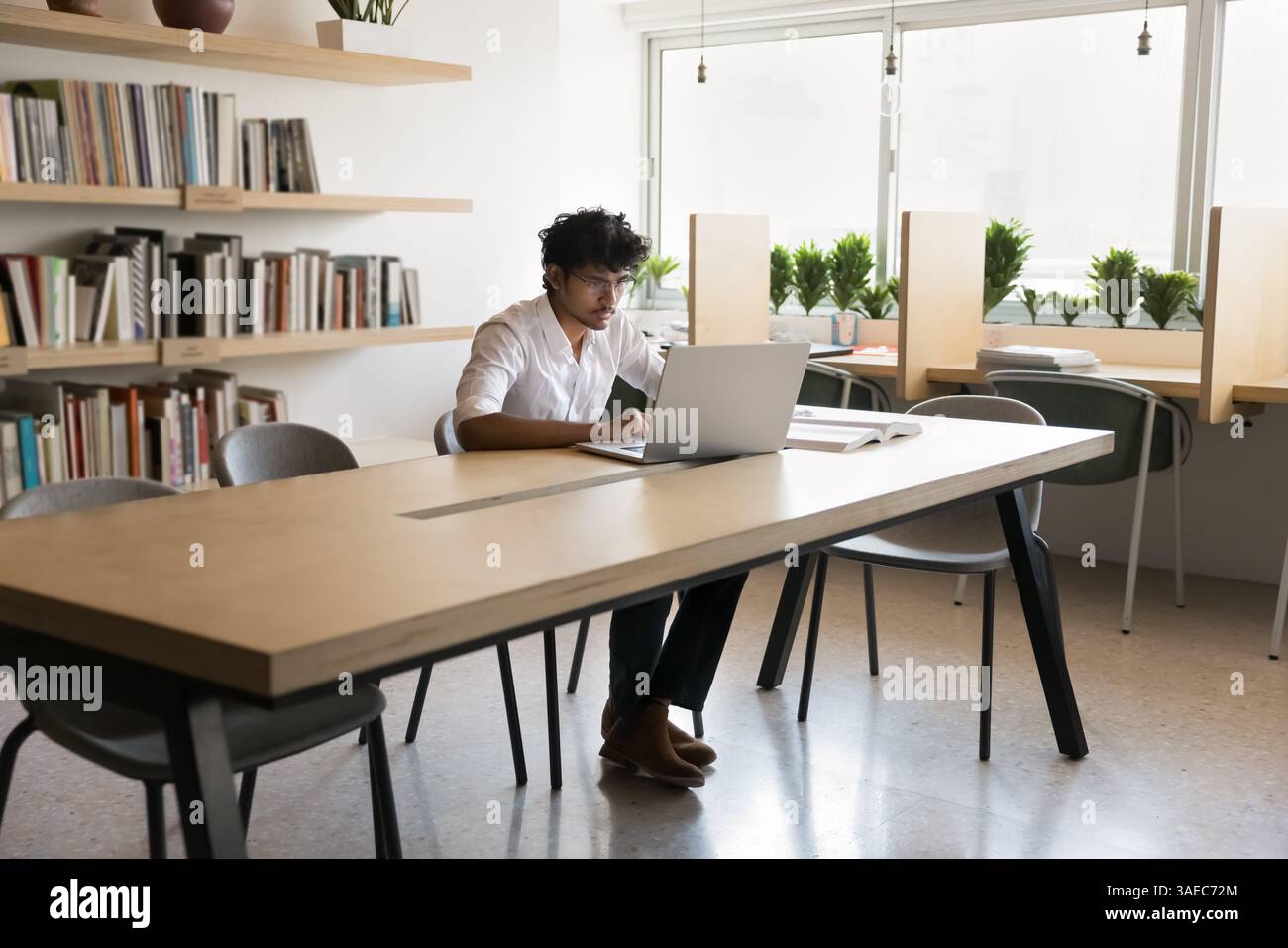 Busy male student engaged in learning at library using notebook Stock Photo