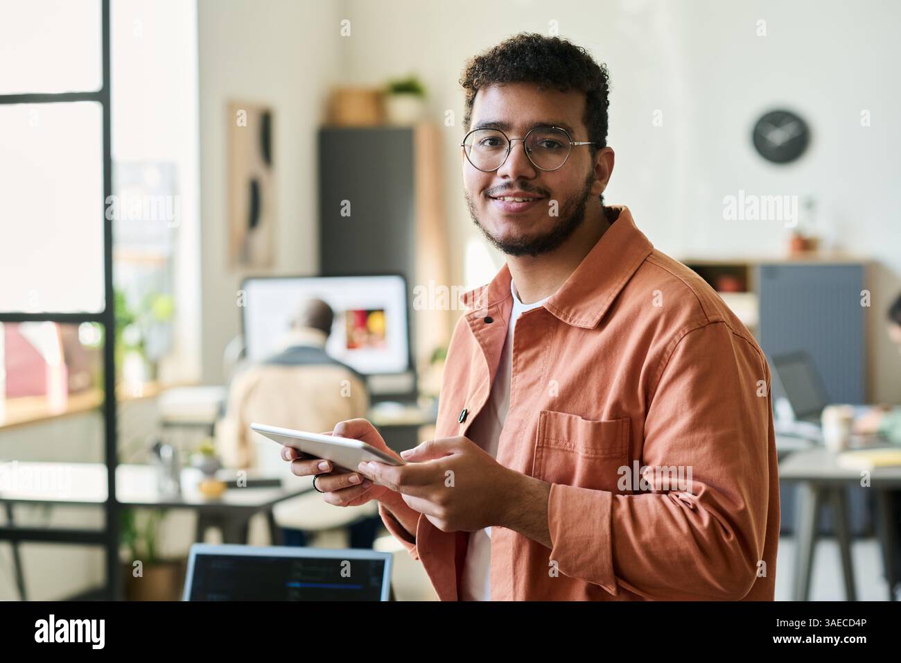 Young smiling male programmer or software developer looking at camera while working over new project in coworking space Stock Photo