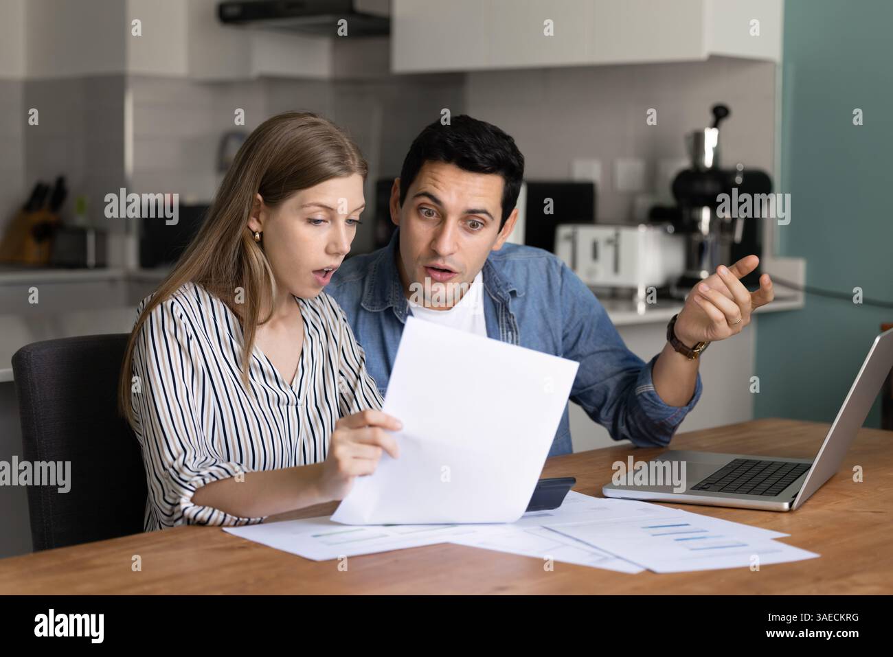 Couple analyzing financial documents with surprised or concerned expressions Stock Photo