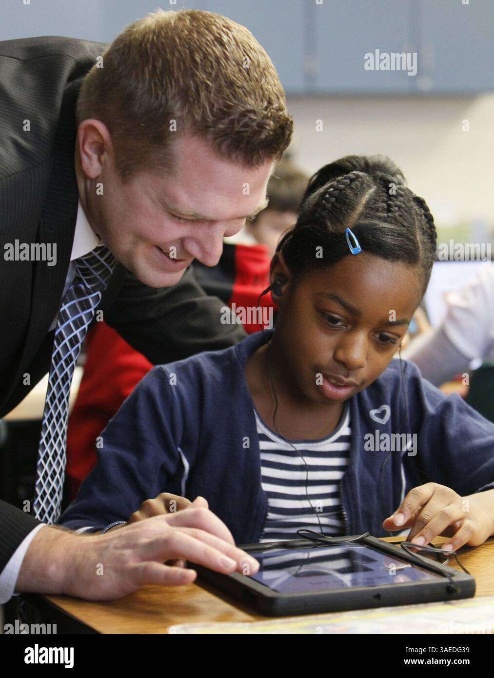 Jan. 5, 2012 - Green, OH, USA - Green Primary School principal Kevin Finefrock, left, interacts with Lynetta Gibson, 8, using an iPad in J.T. Kuzior's third grade class at Green Primary School in Green, Ohio, on Thursday, January 5, 2012. Local entrepreneur Randy Theken has donated the 90 iPads to the school. (Credit Image: © Paul Tople/Akron Beacon Journal/MCT/ZUMAPRESS.com) Stock Photo