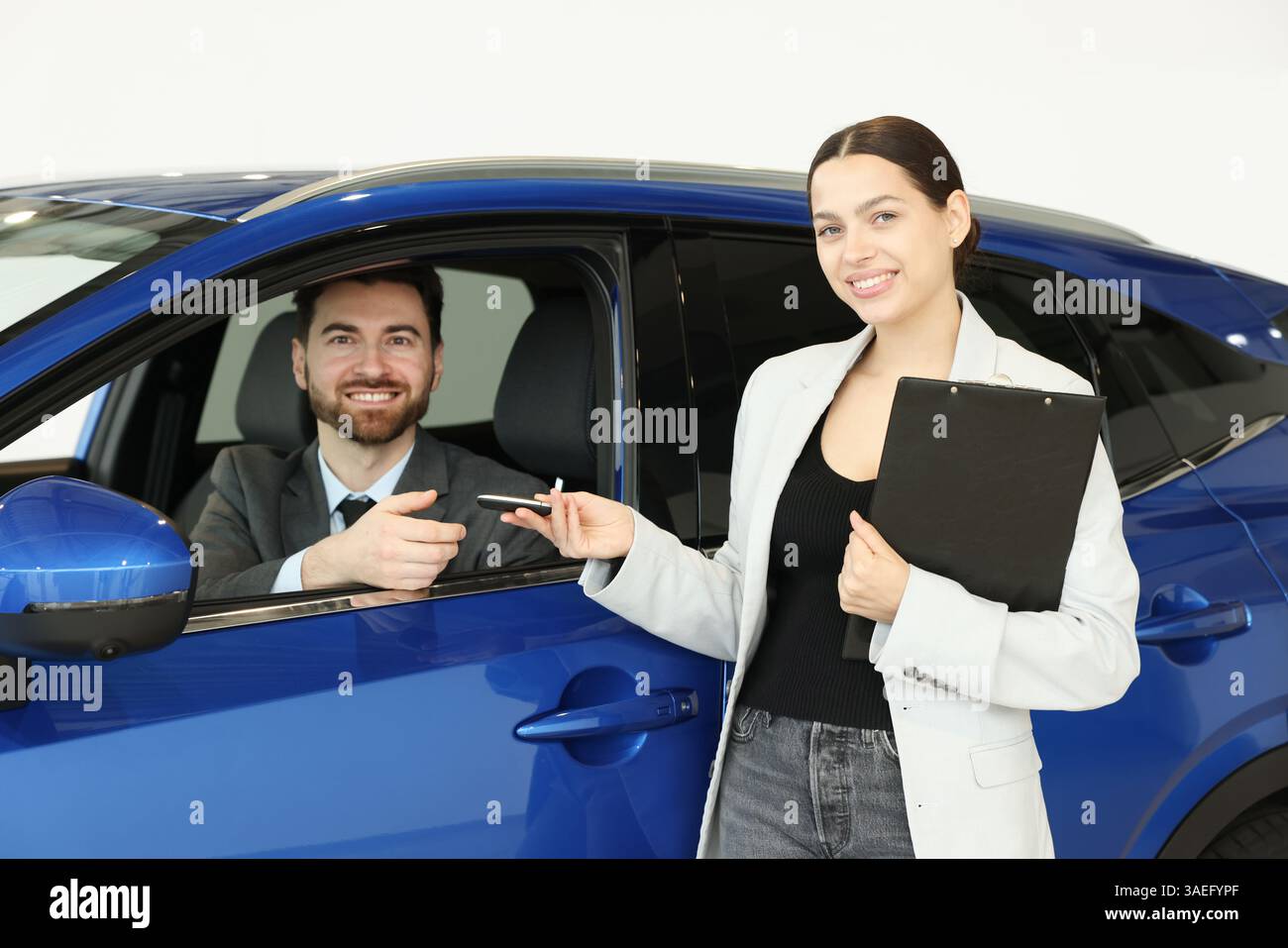 Happy saleswoman giving key to client inside new car in salon Stock ...