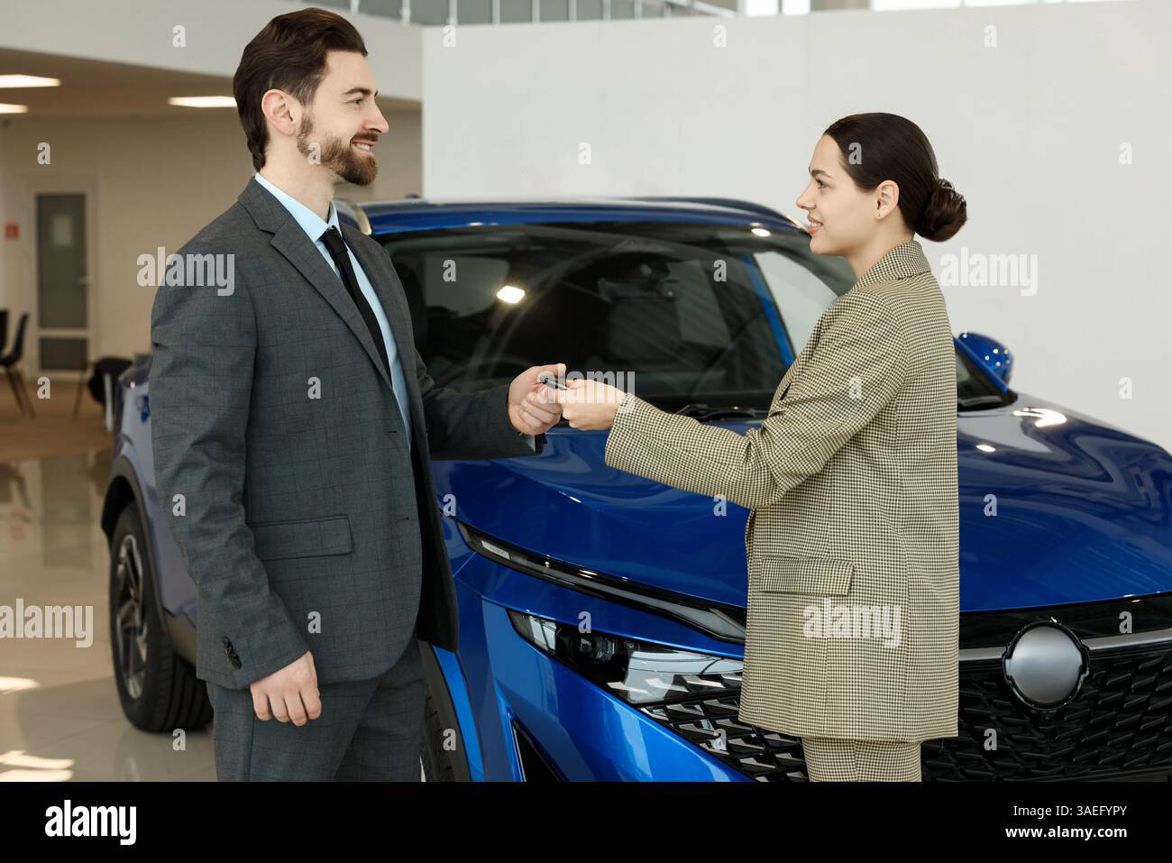 Happy saleswoman giving car key to client in salon Stock Photo - Alamy