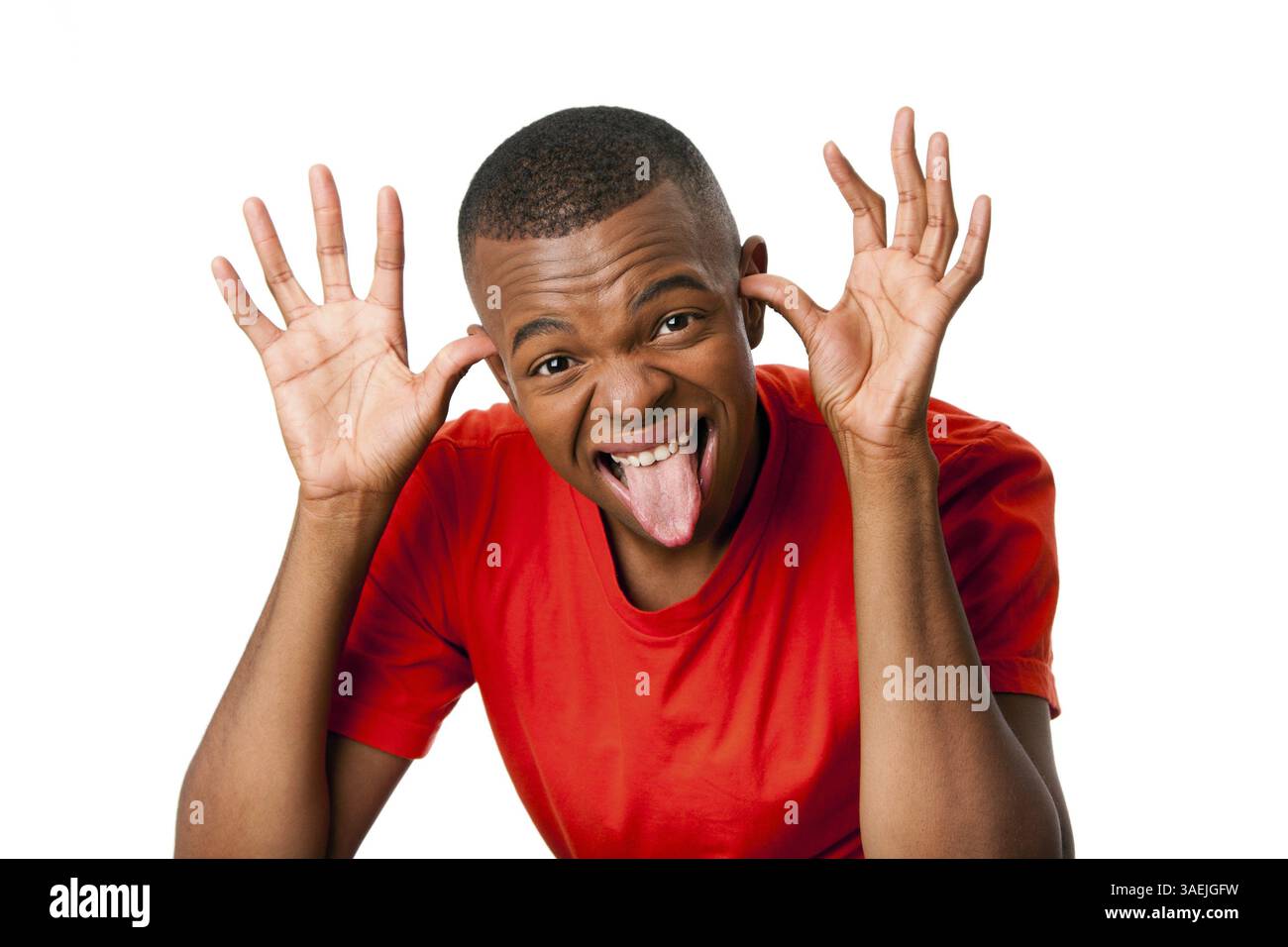 Young man with humorous funny expression sticking tongue out and hands next to face playing peekaboo, isolated, New York, USA, North America Stock Photo