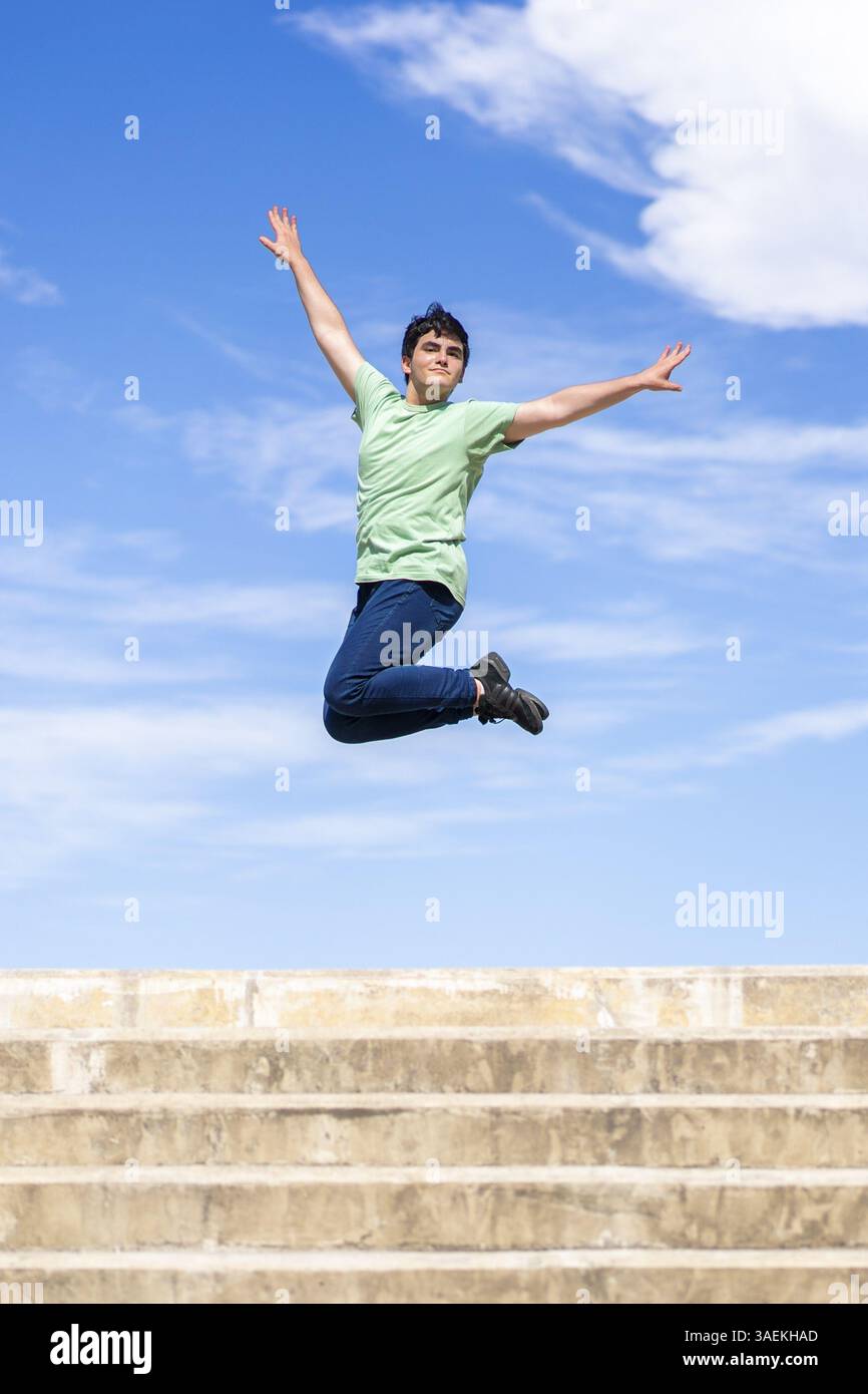 Energetic young man jumping with joy against a clear blue sky Stock Photo