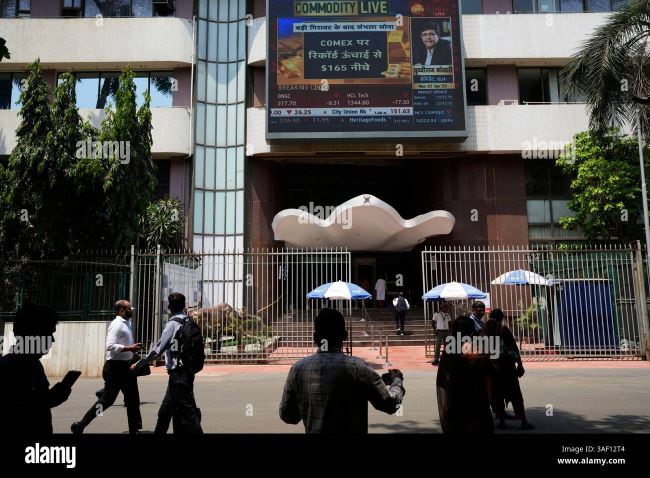 People walk past a live screen on the facade of Bombay Stock Exchange ...
