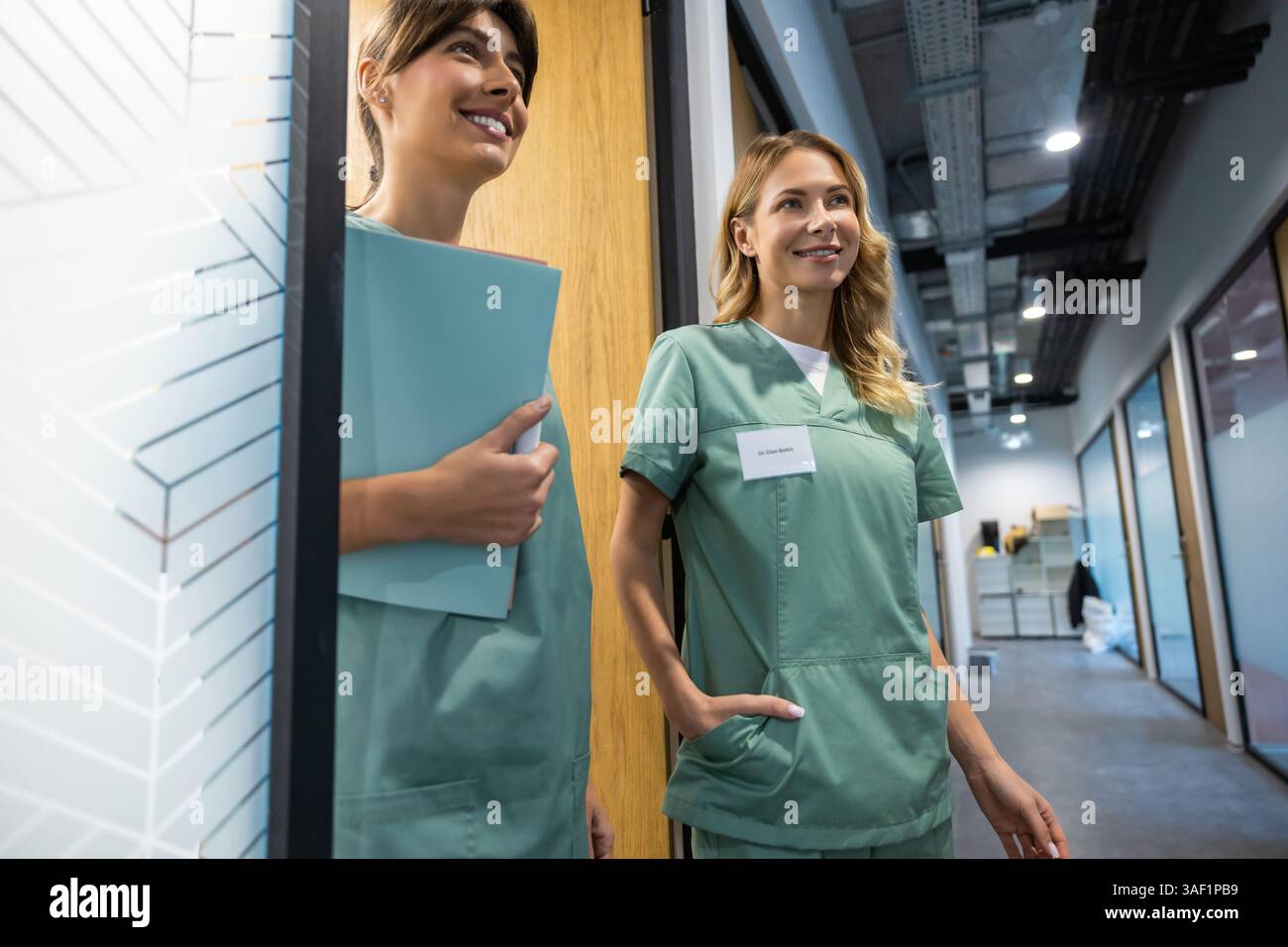 Two female doctors talking in hospital corridor discussing patient's treatment Stock Photo