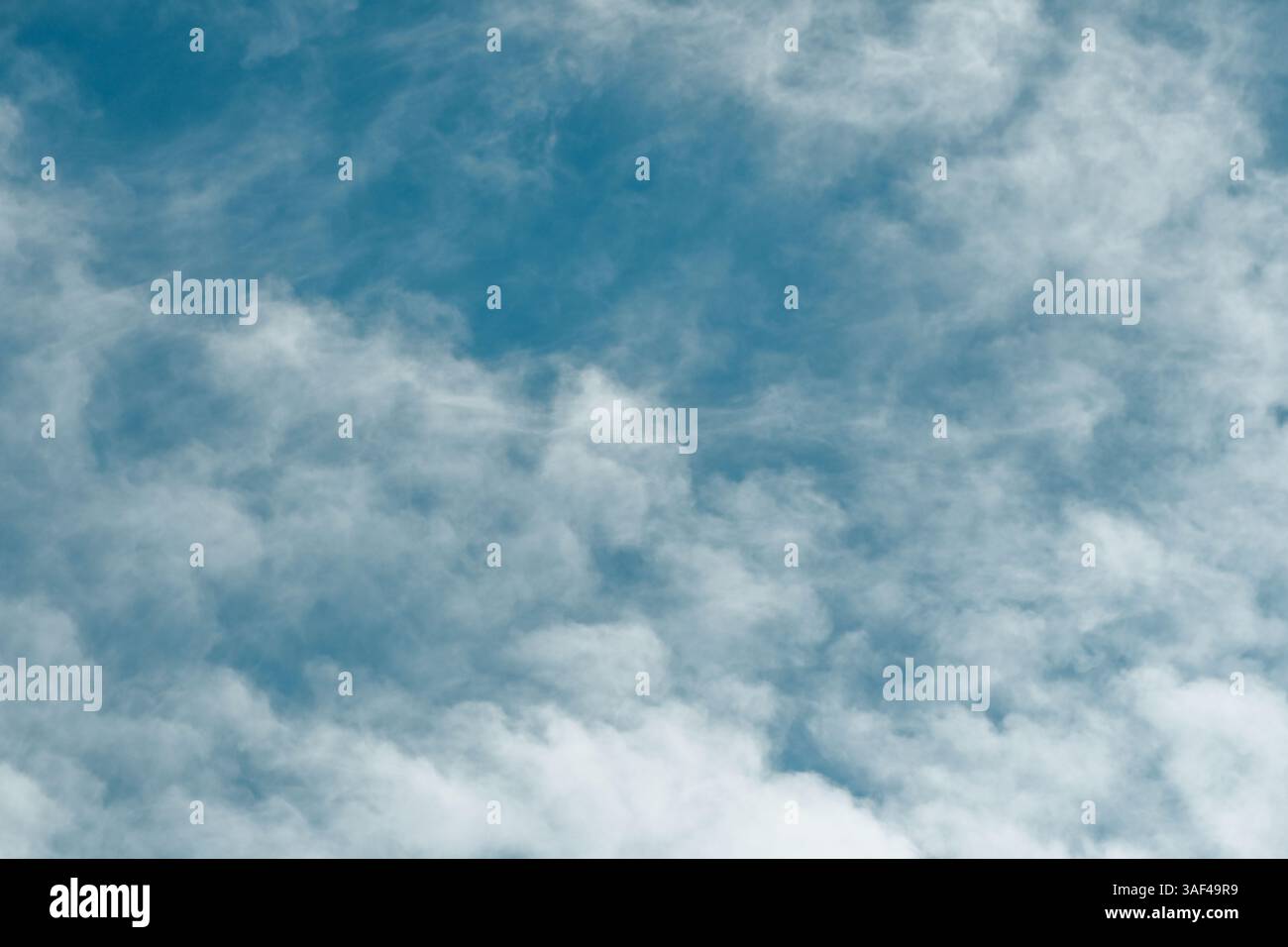 whispy white clouds against blue sky Stock Photo