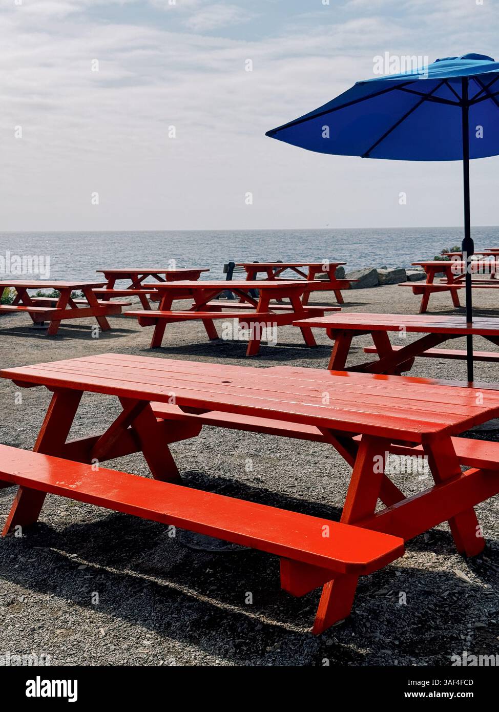 Red picnic tables and blue umbrella by the sea in coastal Maine Stock ...