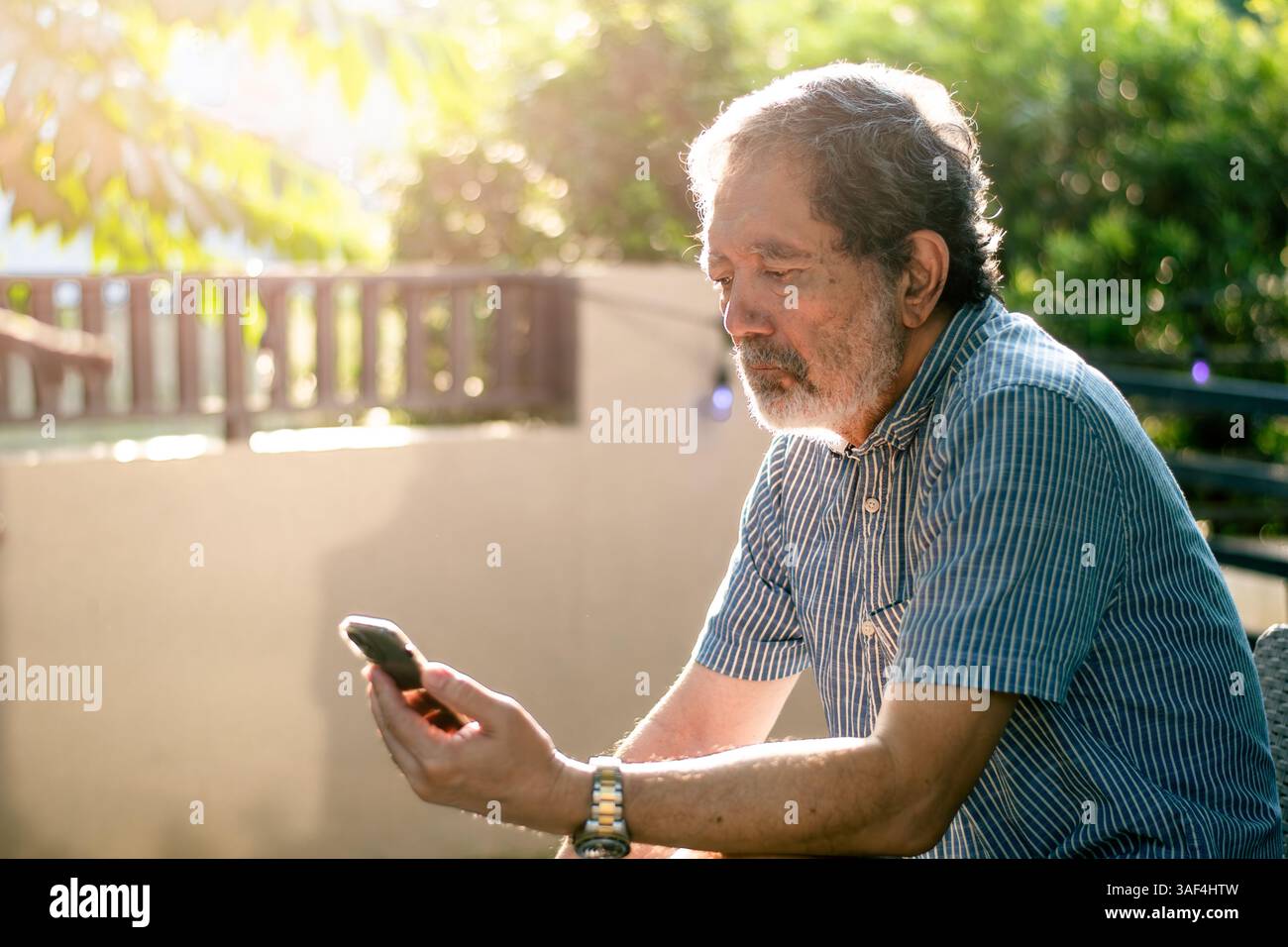 Senior Man using phone outdoors at home Stock Photo