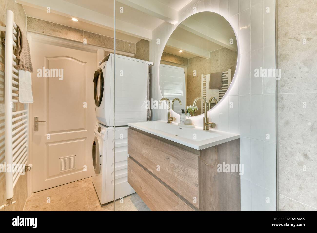 A stylish modern bathroom featuring a sleek sink, washer and dryer ...