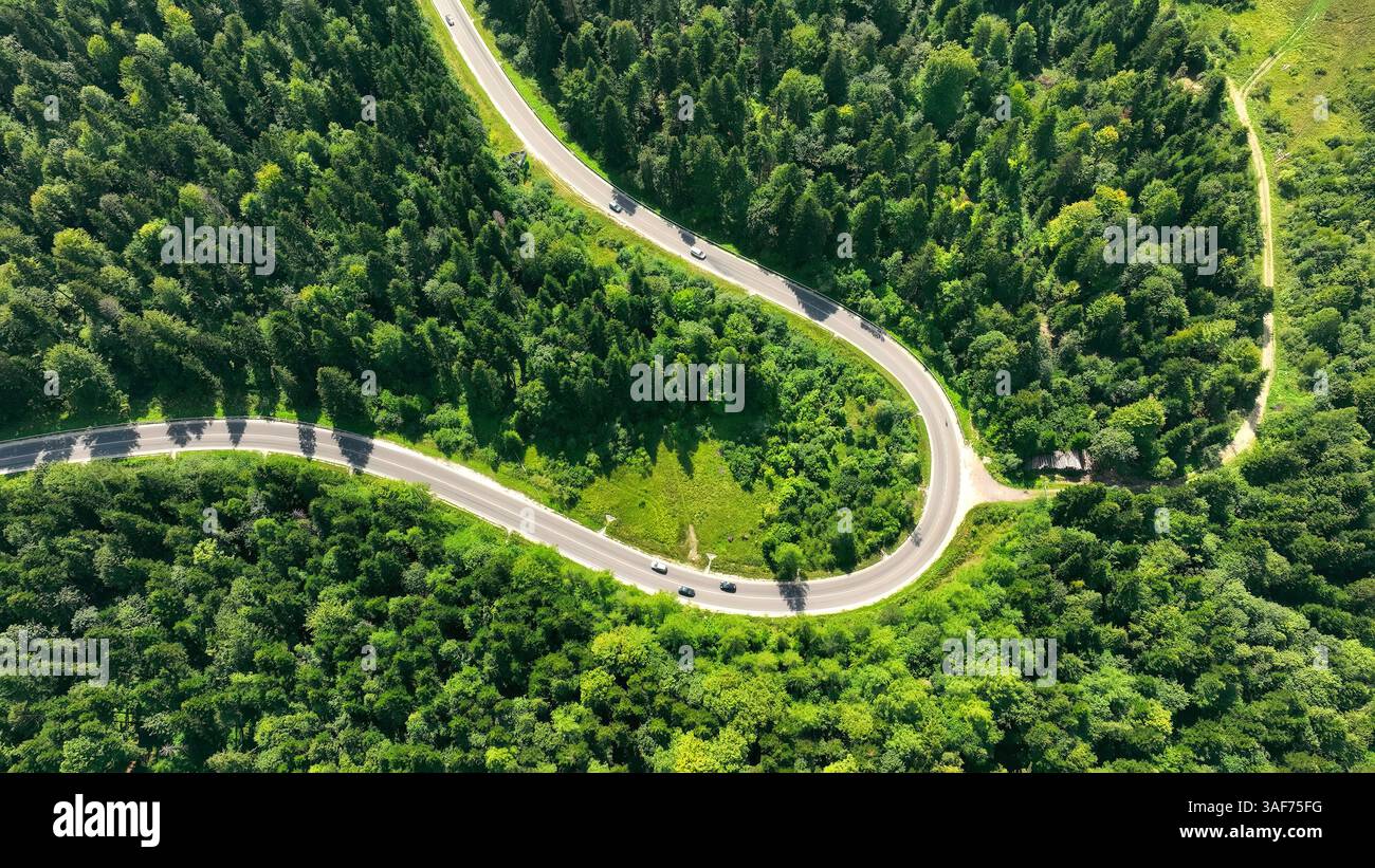 An aerial view of a winding road through dense forest hi-res stock ...