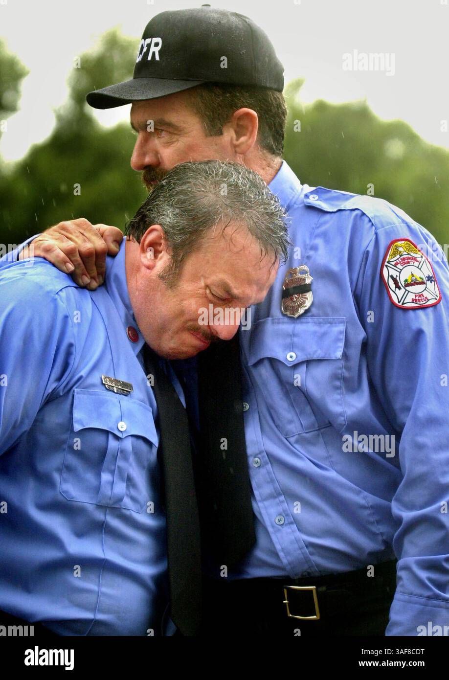 TP 127906 - - DELIVER TO: Tampa - - 9/4/2001 - - Tampa CAPTION INFO: Hillsborough County Fire Rescue firefighter Ray Lopez of Station 19, left, is comforted by George Hernandez, a HCFR driver/engineer from Station 10, after the graveside service for Captain Darryl J. Dzugan of Station 14. Dzugan, 36, died of a heart attack Wed. Aug. 29, after fighting a fire. Dzugan was remembered by hundreds of family, friends and fellow rescue workers from all over the state at a memorial service Tuesday morning at the USF Sundome. - - Times Photo by: Stefanie Boyar Story By: - - SCANNED BY: - - RUN DATE: 9/ Stock Photo
