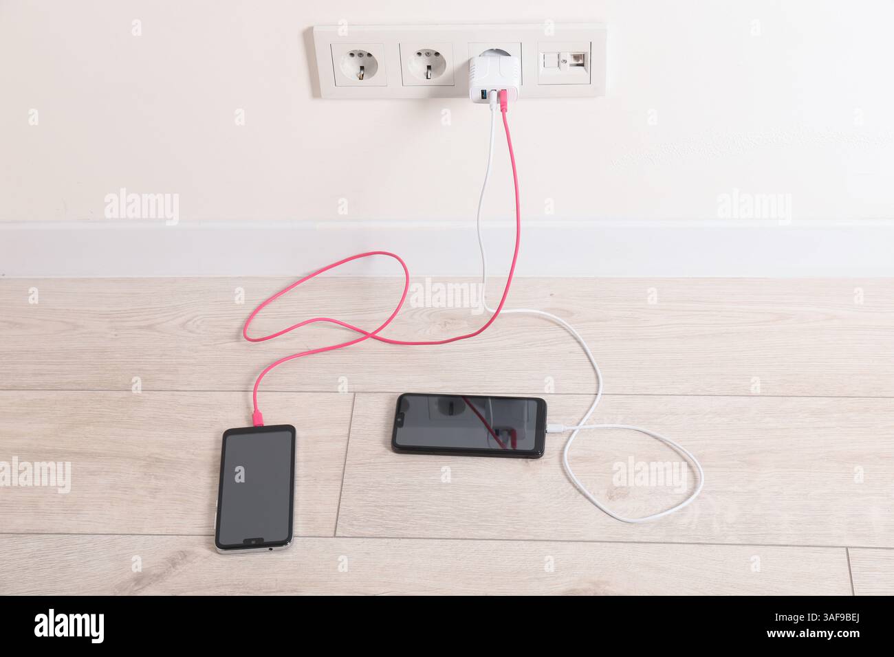 USB adapter with cables plugged into electric socket charging different ...
