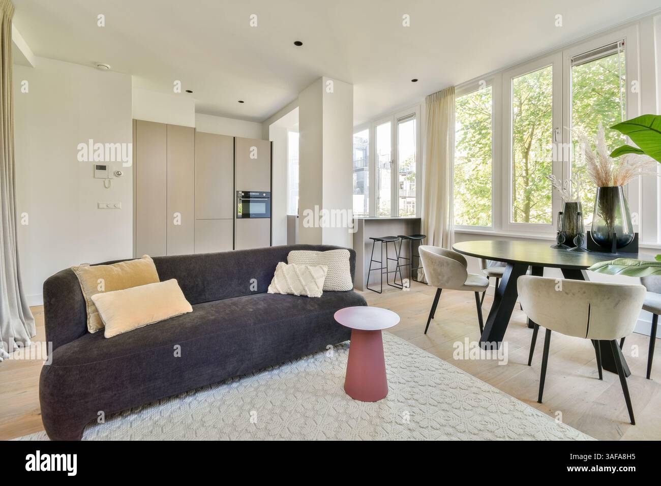 A stylish modern living room featuring large windows, a cozy sofa, and ...