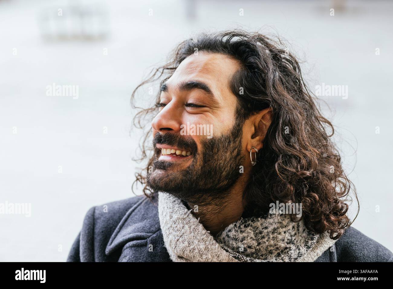 Portrait of smiling man with long hair and earring enjoying winter day Stock Photo