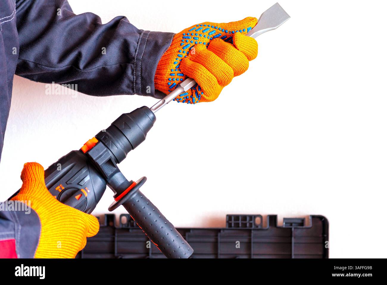close-up. hands in protective gloves, hammer drill, installation of a chisel in a perforator. The concept of replacing the rotary drill. Stock Photo