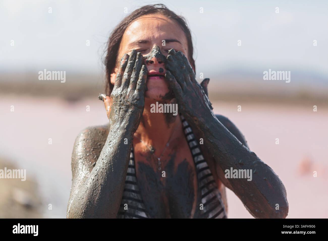 Woman applying mineral mud to face in spa ritual Stock Photo - Alamy