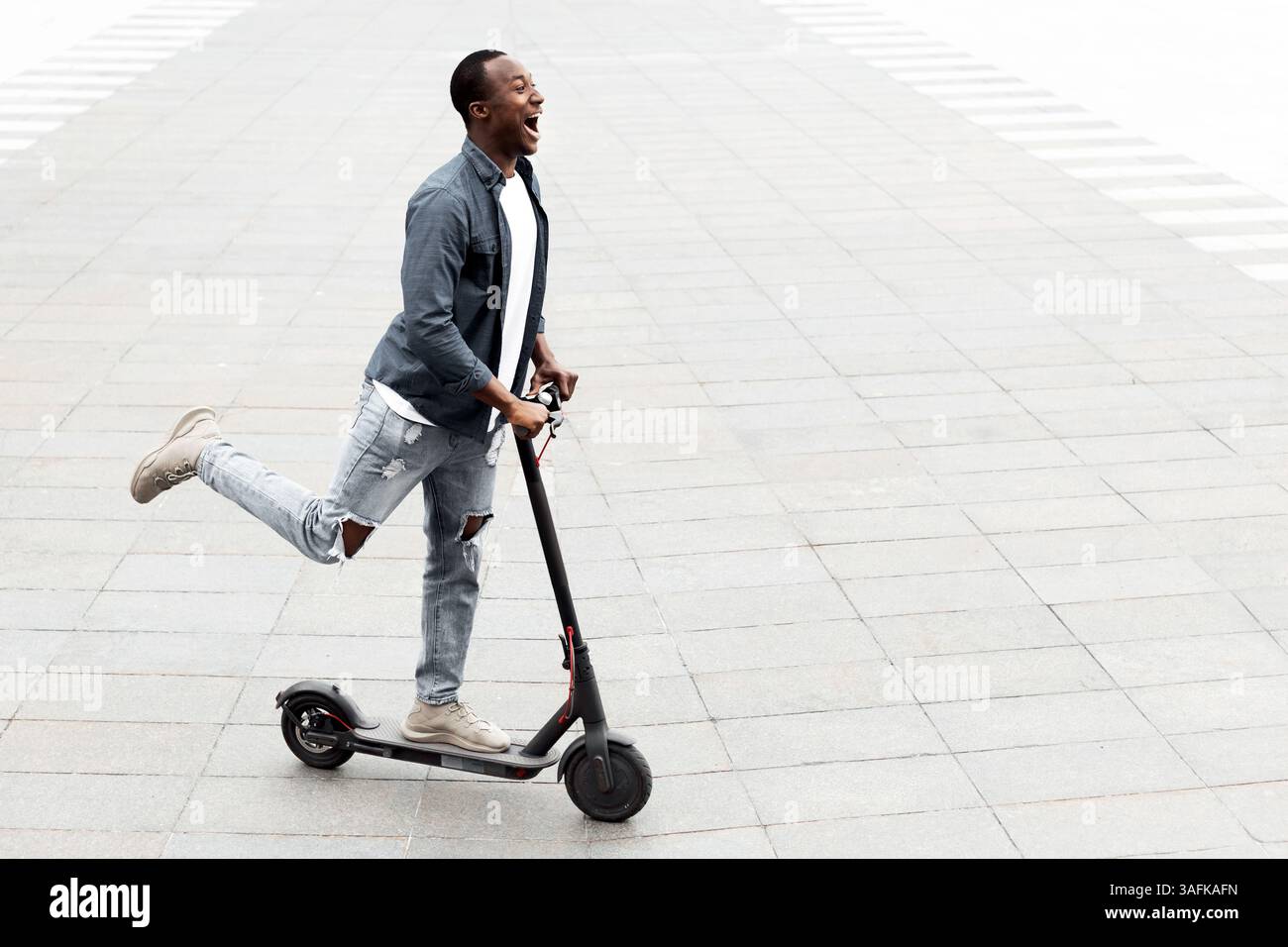Guy having pleasant ride on electric kick scooter Stock Photo