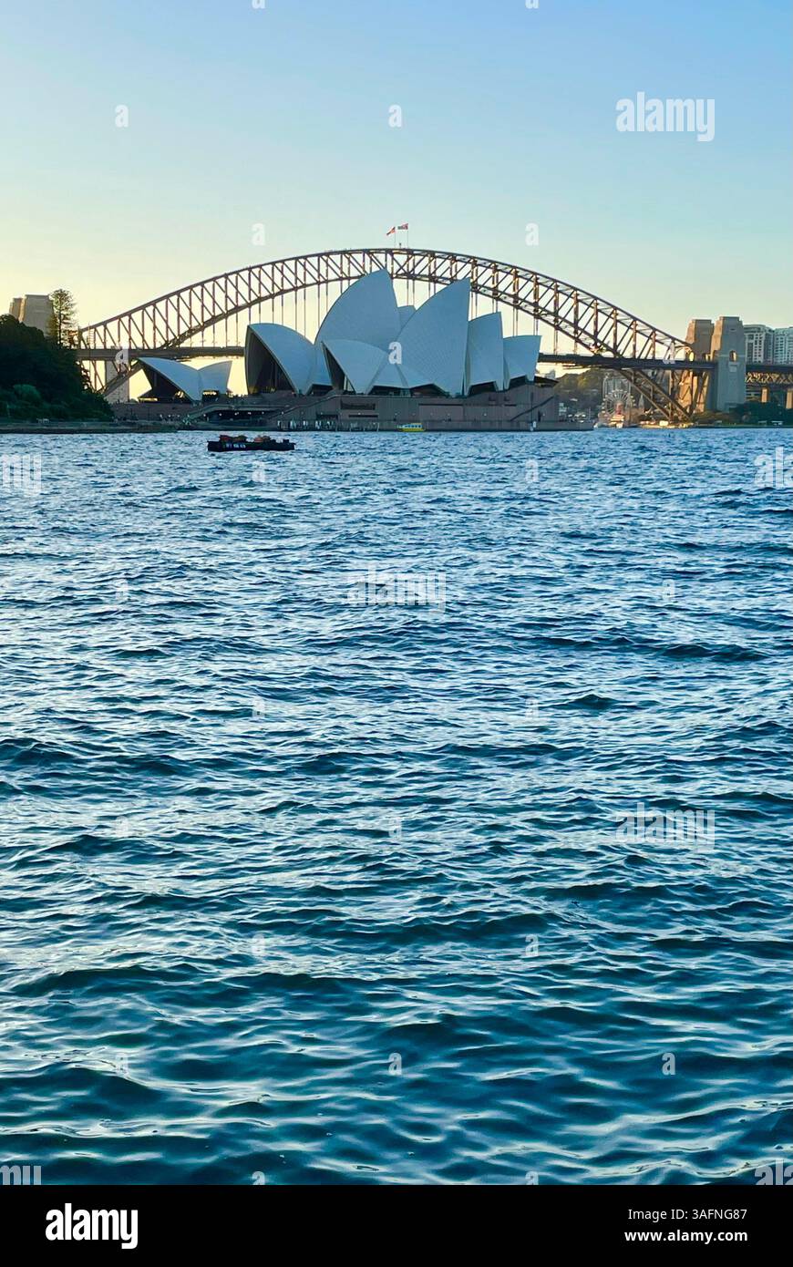An alternative view of Sydney Opera House as it is framed by Sydney Harbour Bridge at sunset in New South Wales, Australia - Smartphone Captured Stock Image