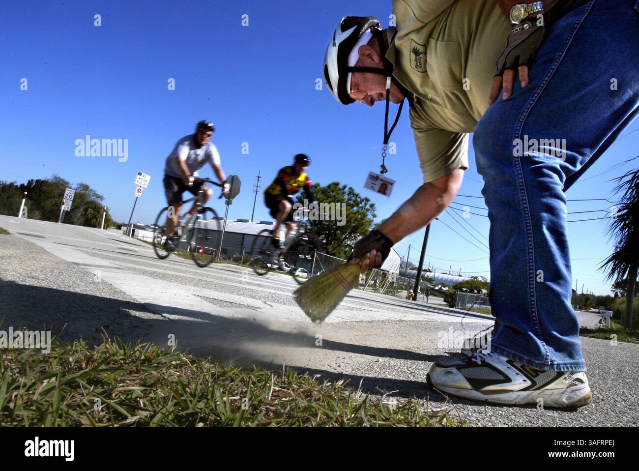 CAPTION: Palm Harbor - Monday (2/6/2006) - 1) Volunteer ranger Nova Bickell (CQ), 57, of Palm Harbor, uses a wisk broom to clear pebbles and dirt from the intersection of Florida Avenue and the Pinellas Trail while on one of his five weekly bicycle rides Monday (2/6/2006) in Palm Harbor. Bickell said he rides between 90-120 miles each week on the trail looking for hazards which could hurt cyclists, joggers, pedestrains or skaters. He said he patrols as the eyes and ears of the county but also does it for his wife, Lorraine Bickell (Credit Image: St Petersburg Times/ZUMAPRESS.com) Stock Photo