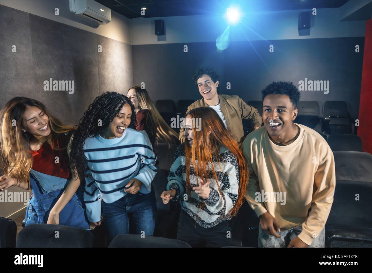 Happy multi ethnic friends dancing and celebrating together at a lively movie disco event in the cinema, enjoying every moment of fun Stock Photo