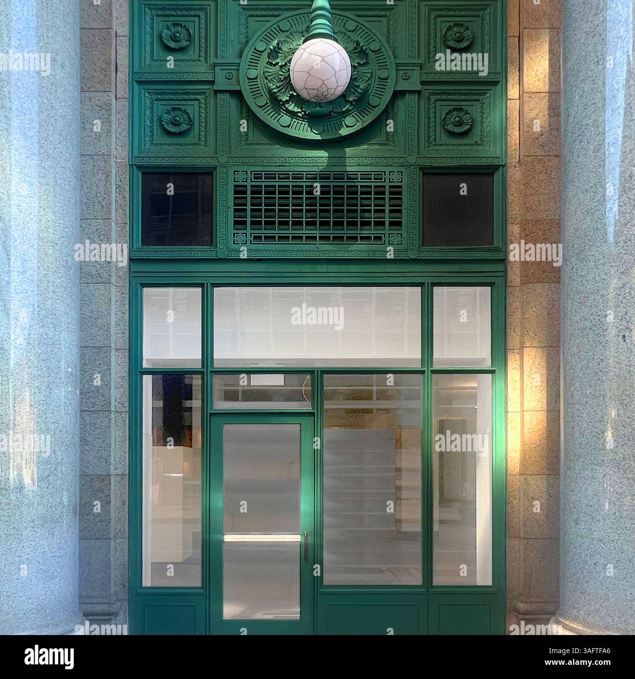 Green downtown Chicago entrance dramatically framed by carved marble columns, merging vivid color with timeless architectural detail - Smartphone Captured Stock Image