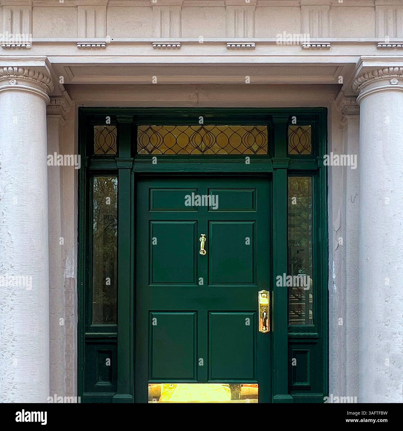 Elegant dark green door with gold hardware and stained glass transom, framed by classical white columns and detailed stonework on a historic Chicago - Smartphone Captured Stock Image