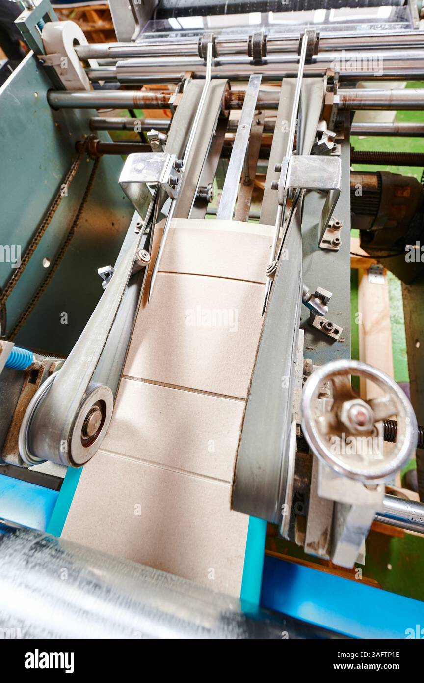 Efficient cardboard box flap folding machine in action at a bustling ...